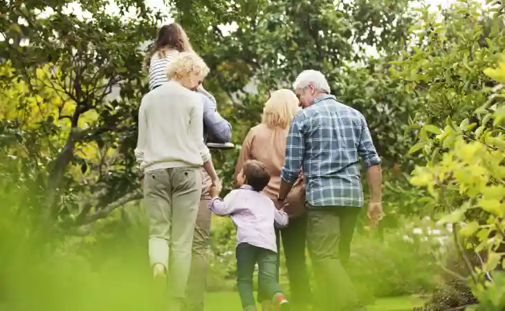Multiple generations of a family walk through a lush wooded garden.